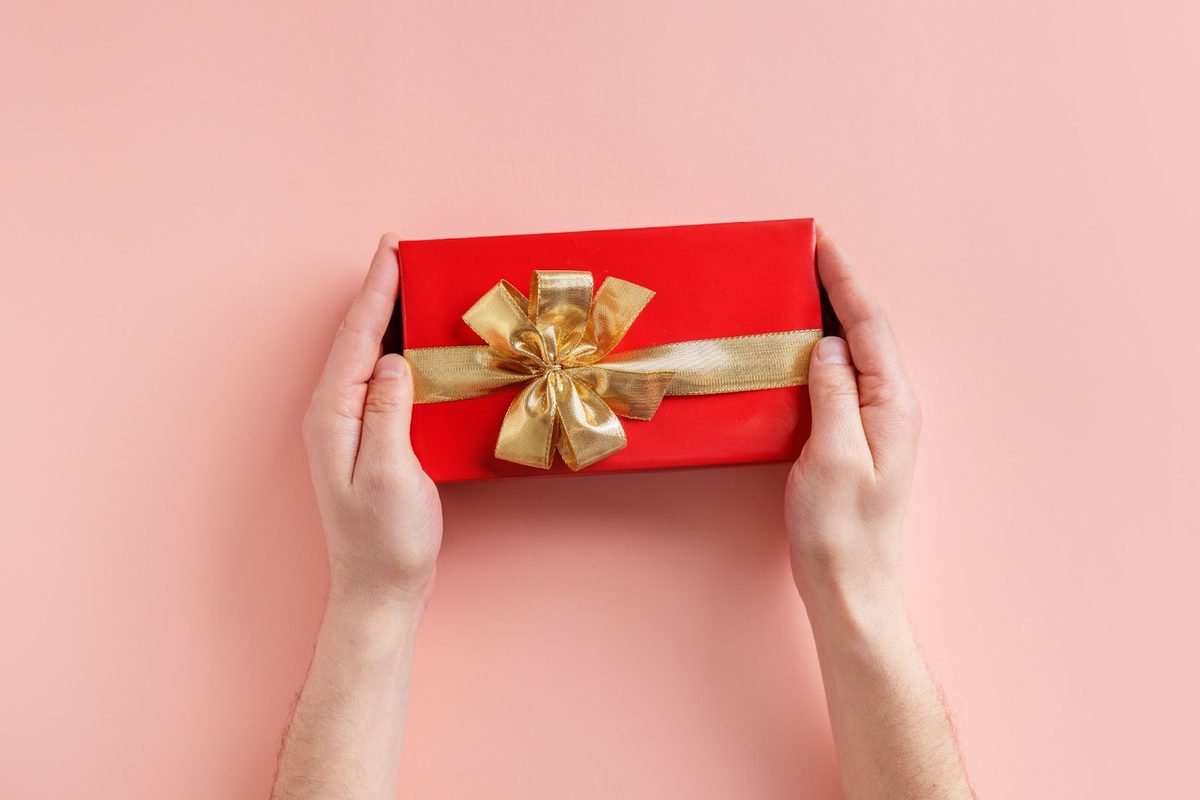 Man holding a gift box with a golden ribbon