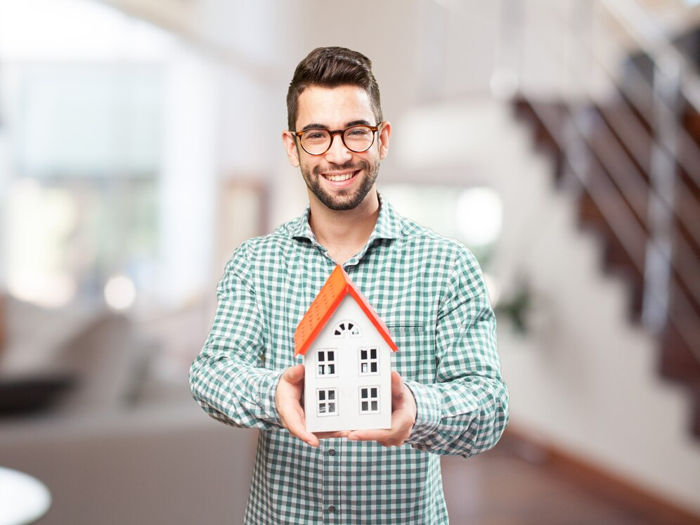 Happy man holding a miniature model of his future home