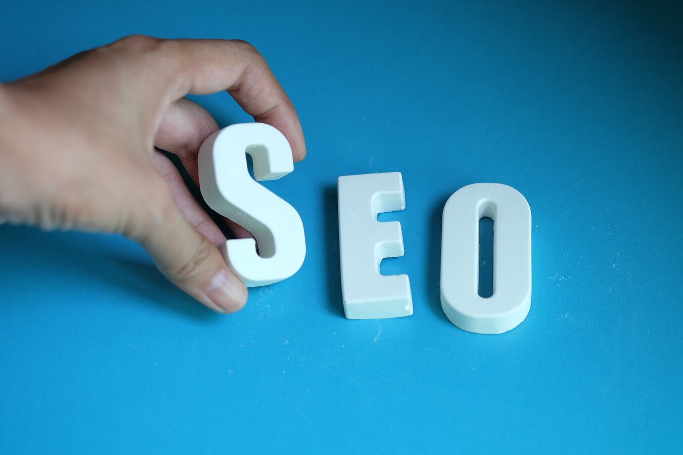 Hand arranging white letters spelling SEO