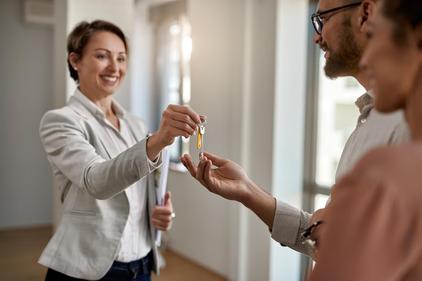 Happy real estate agent handing keys to a couple at their new home